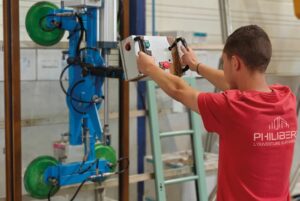 Un menuisier chez Philibert déplaçant un vantail grâce à une machine